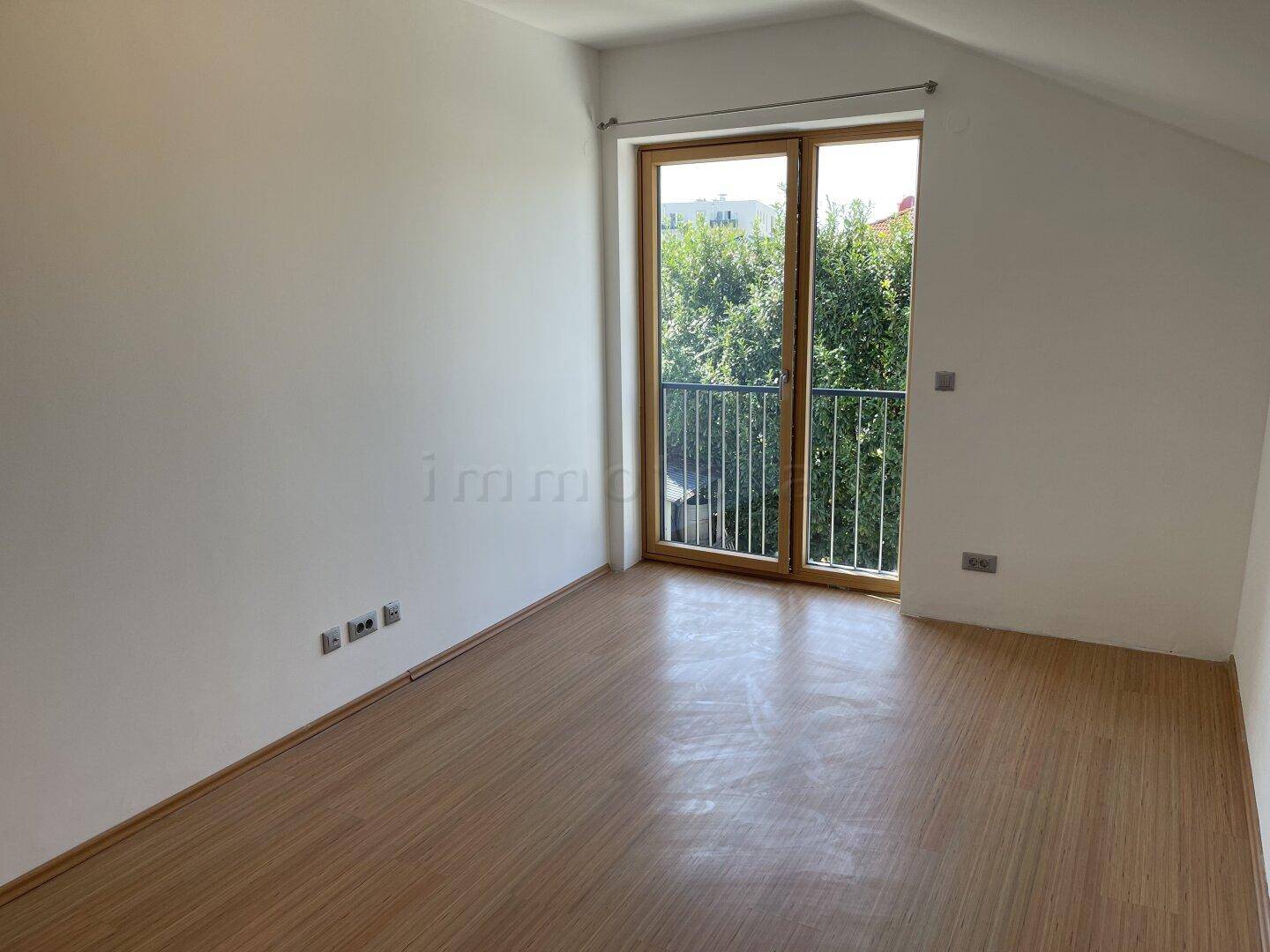 Helles Zimmer mit Holzboden und französischem Balkon, bietet viel Tageslicht.