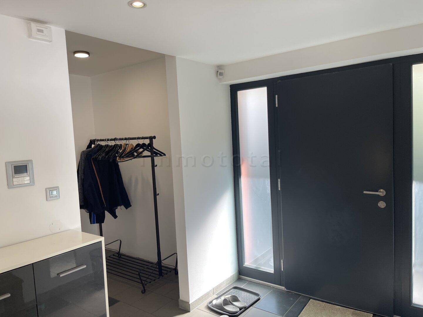 Heller Eingangsbereich mit Garderobe und moderner Haustür.