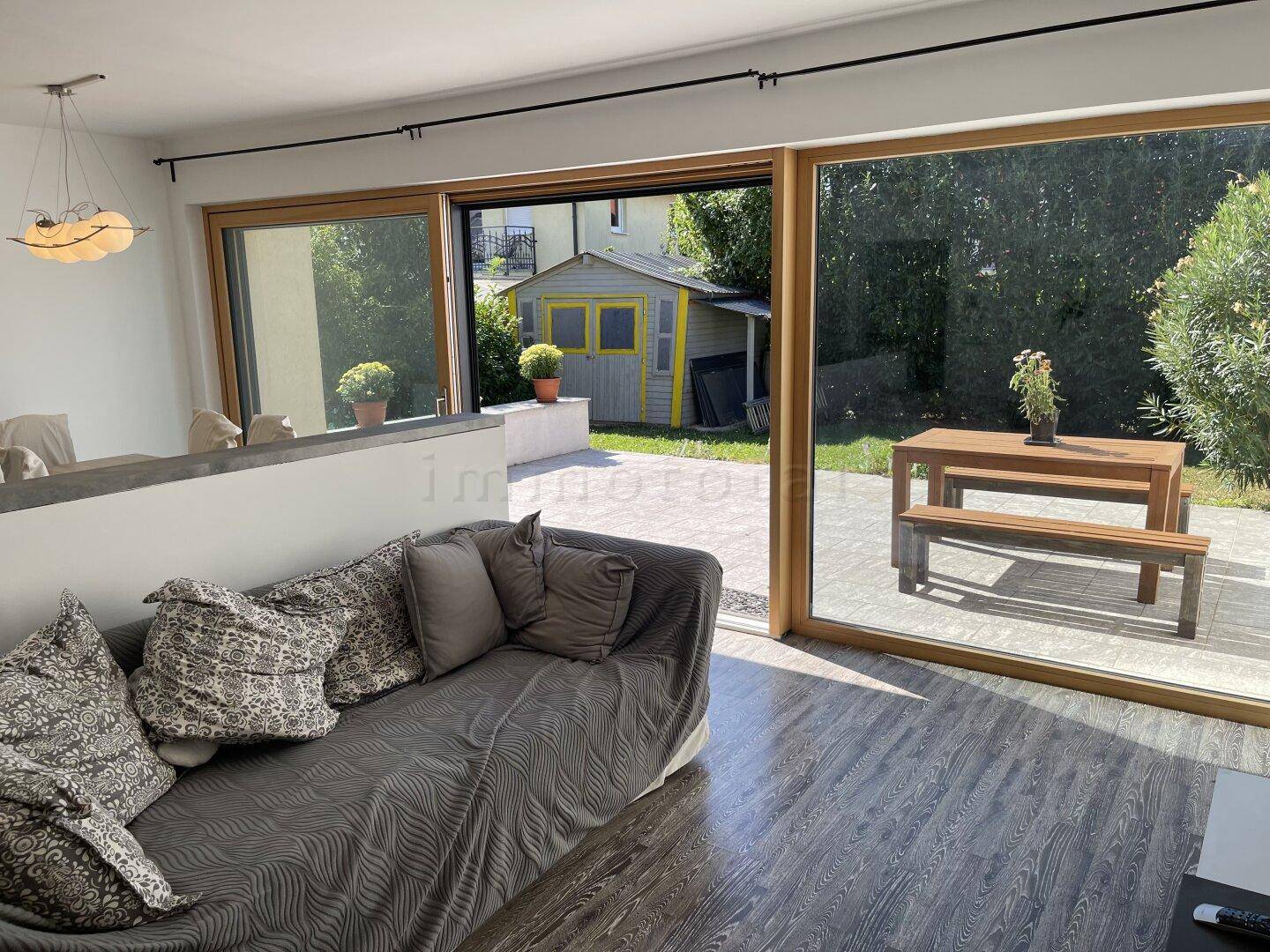Helles Wohnzimmer mit Holzboden und Zugang zur Terrasse mit Gartenblick.