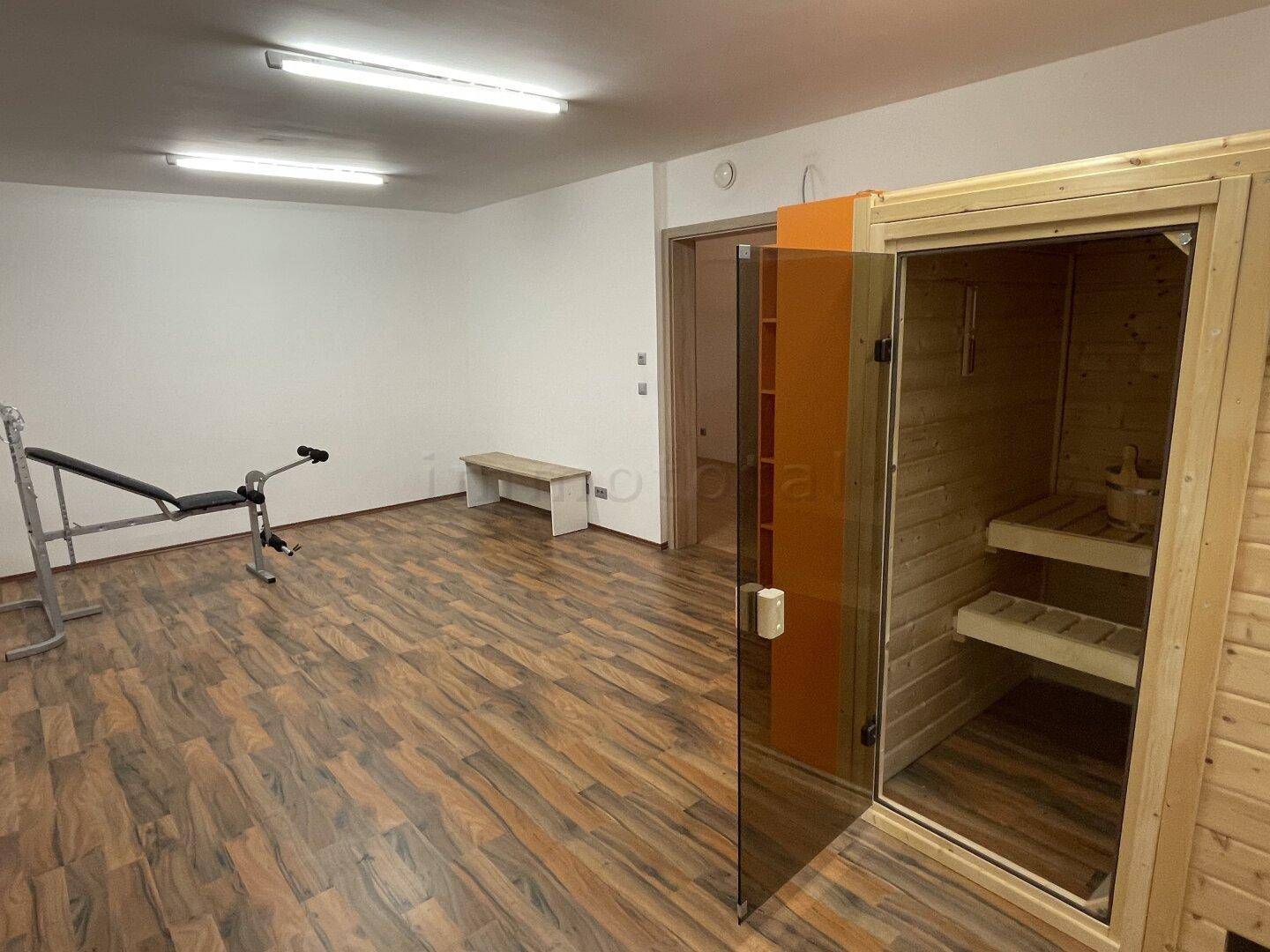 Geräumiger Fitnessraum mit Sauna und Trainingsgeräten für private Wellness-Momente.