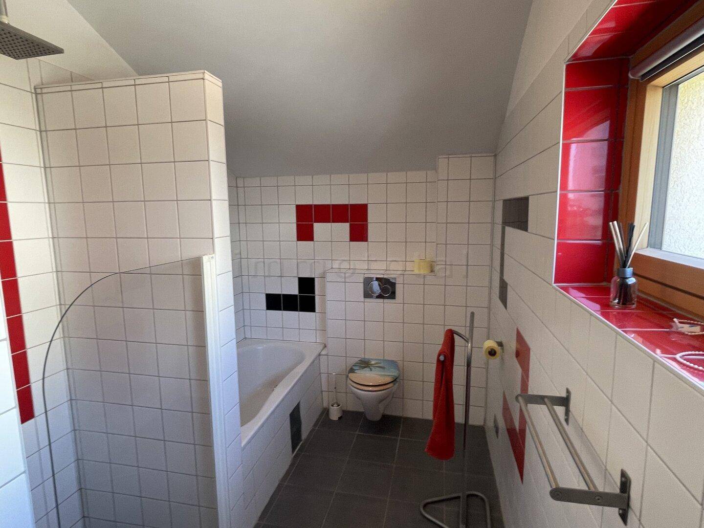 Modernes Badezimmer mit Badewanne, Dusche und farbigen Akzentfliesen.