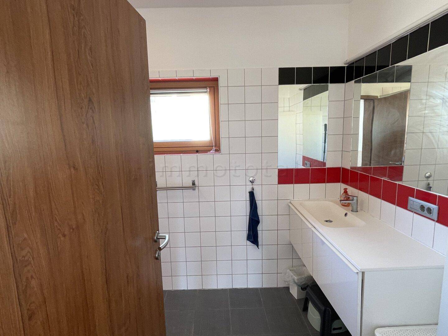Badezimmer mit großem Waschtisch, Spiegeln und Fenster.