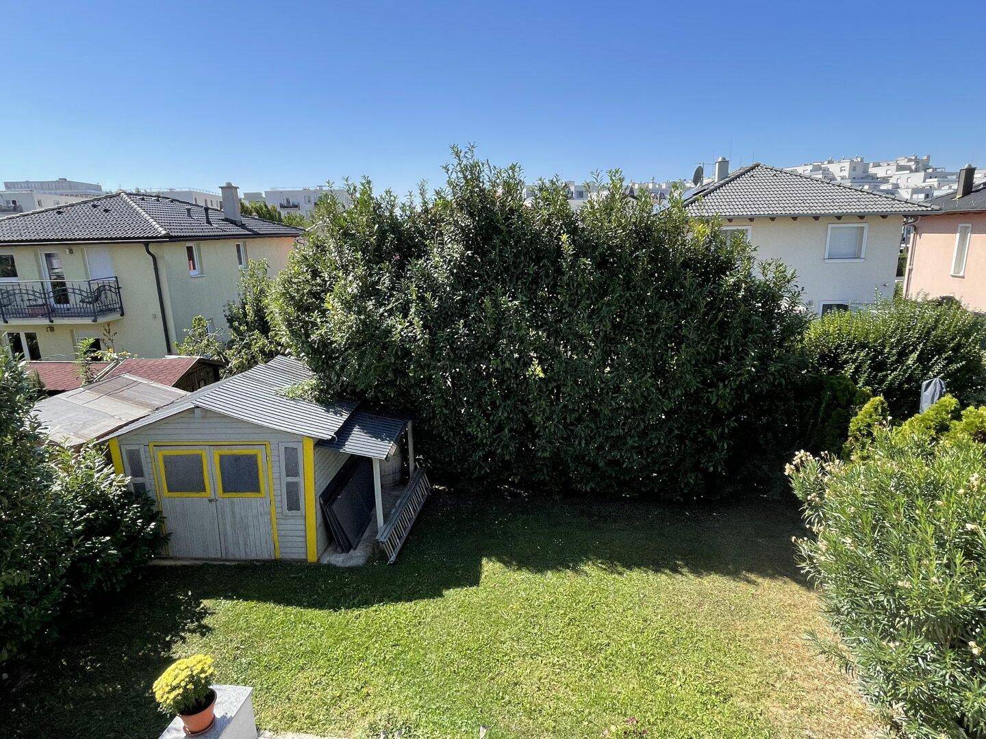 Blick von oben auf den Garten mit Gartenhaus und die umliegende Nachbarschaft.