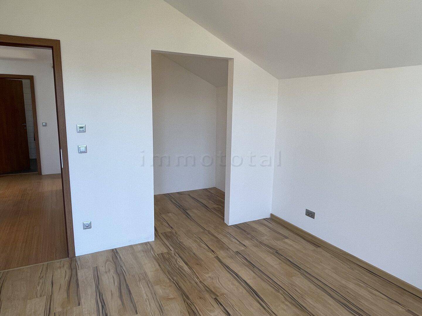 Helles Zimmer mit Holzboden und praktischer Nische für einen Einbauschrank.