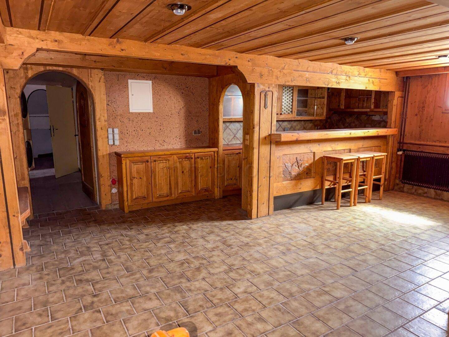 Rustikaler Partykeller mit Holzvertäfelung, Bar und Fliesenboden, ideal für Geselligkeit.