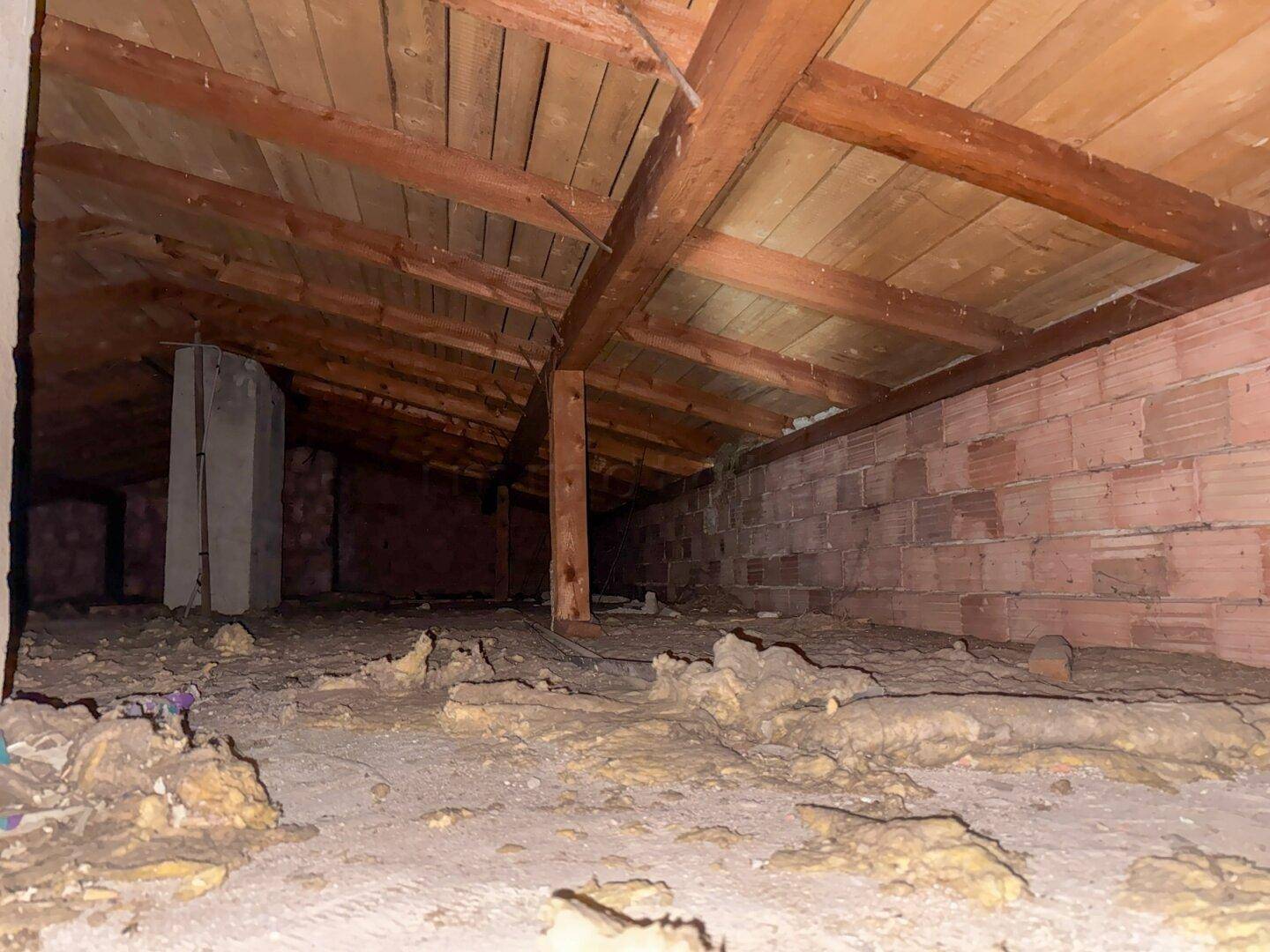 Dachboden mit sichtbaren Holzbalken und unfertigem Boden, bietet Ausbaupotenzial.