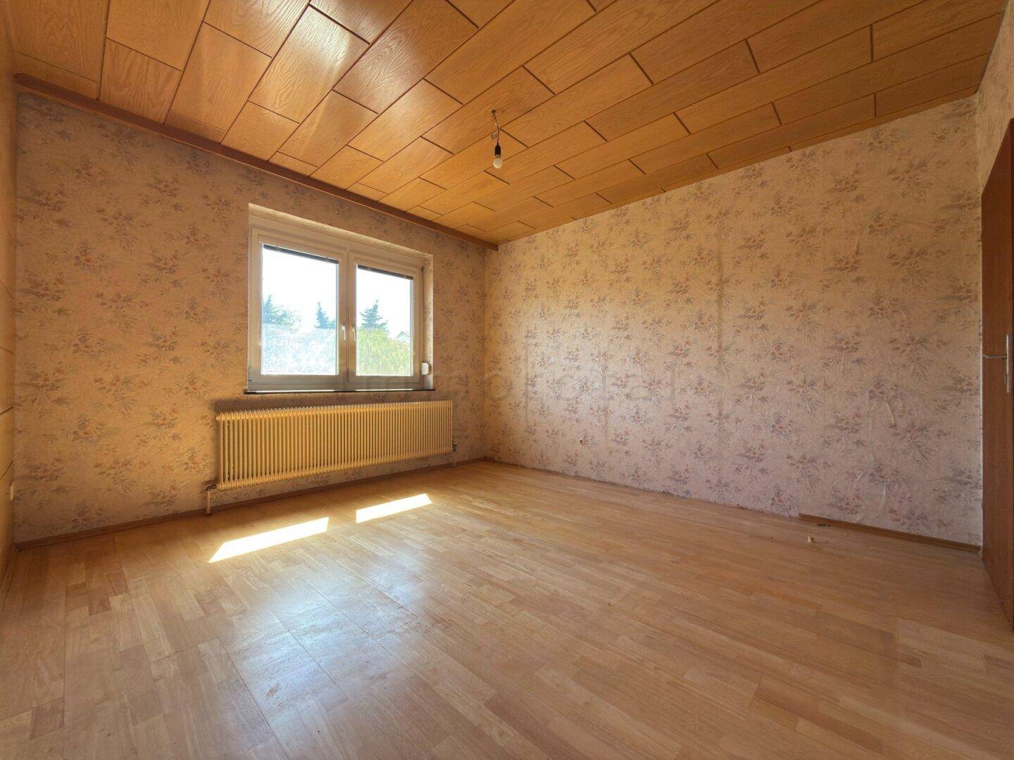 Schlafzimmer mit Laminatboden, Holzdecke und Fenster, bietet viel natürliches Licht.