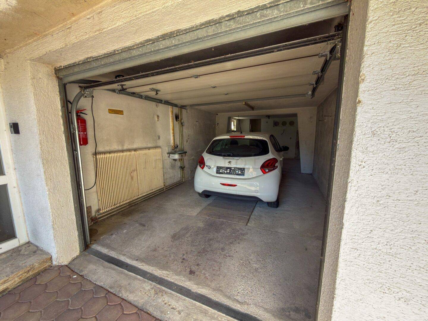 Garage mit einem geparkten Auto und Heizkörper, bietet sicheren Stellplatz.