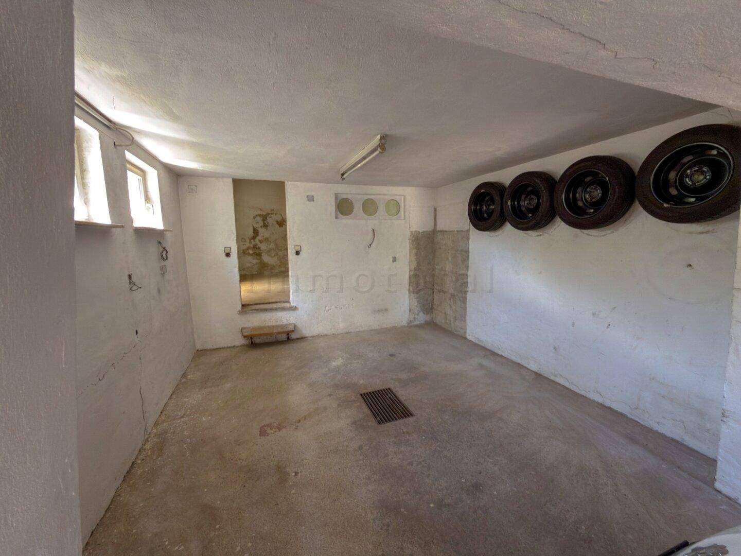Leere Garage mit Betonboden und Reifen an der Wand, bietet viel Stauraum.