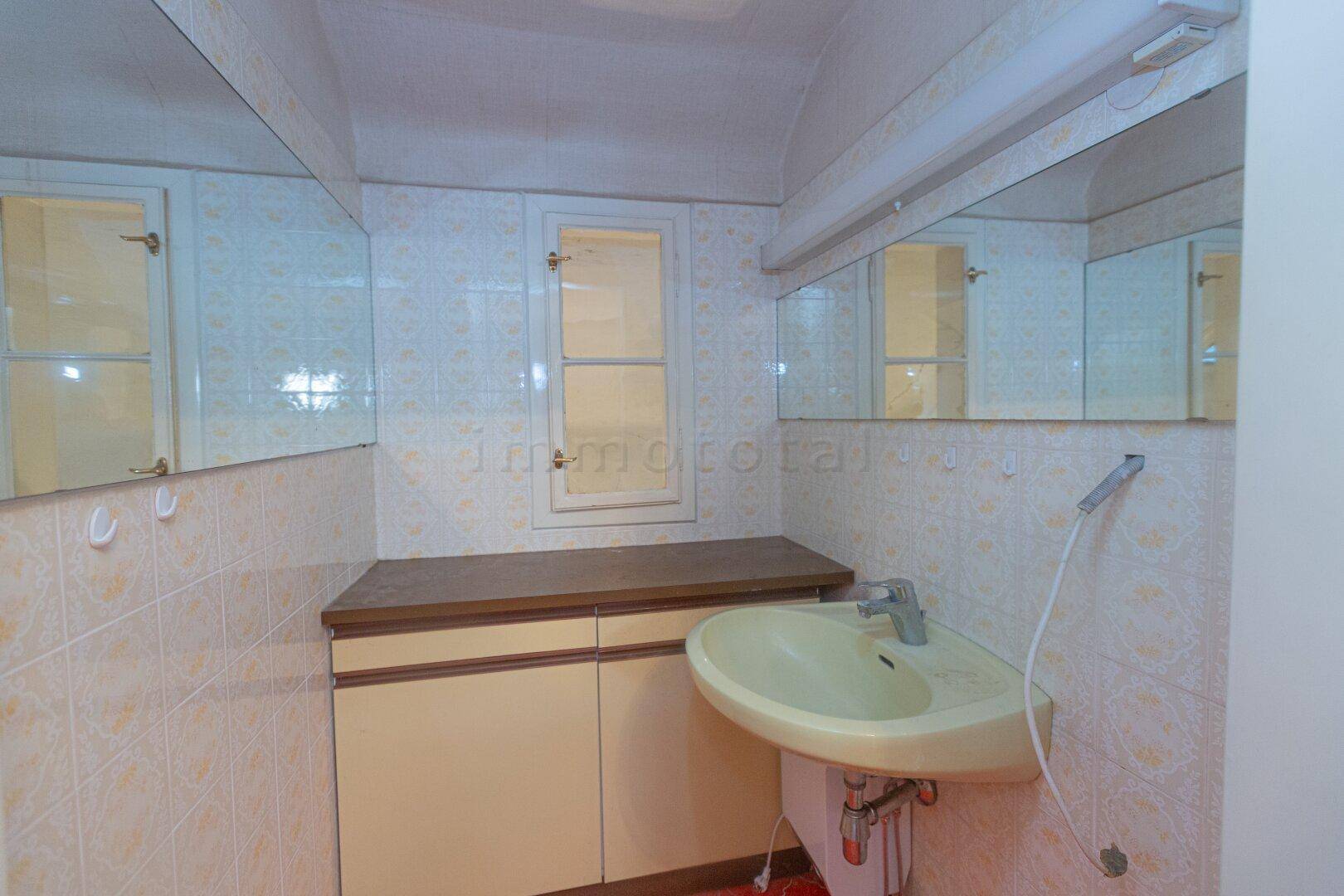 Badezimmer mit gelbem Waschbecken, Spiegelschrank und Fenster.
