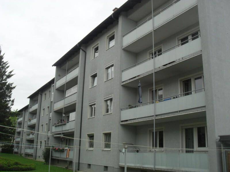 Ansicht eines Mehrfamilienhauses mit Balkonen und Rasenfläche im Vordergrund.