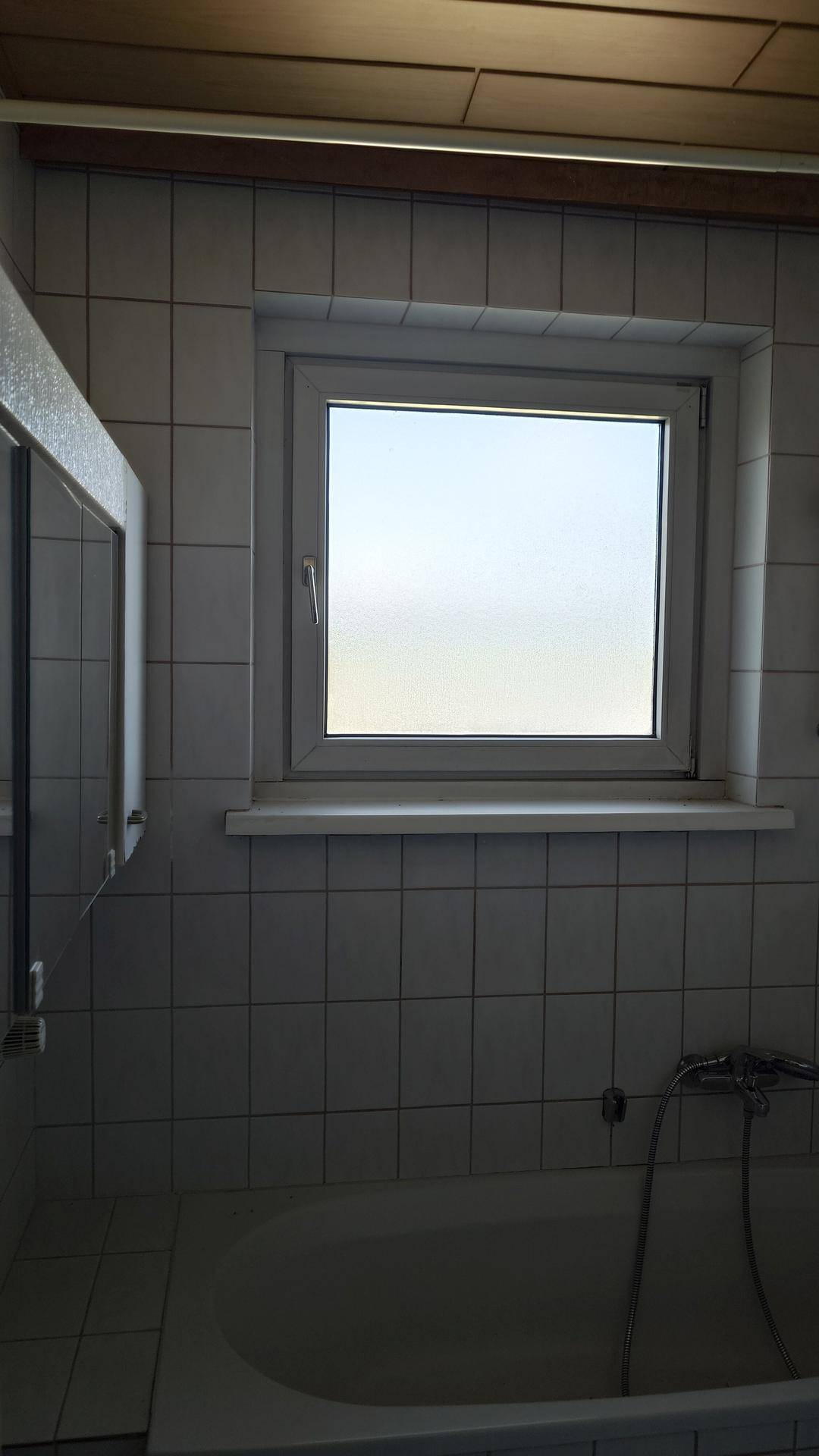 Badezimmer mit Badewanne und Fenster, gefliest in hellem Design.
