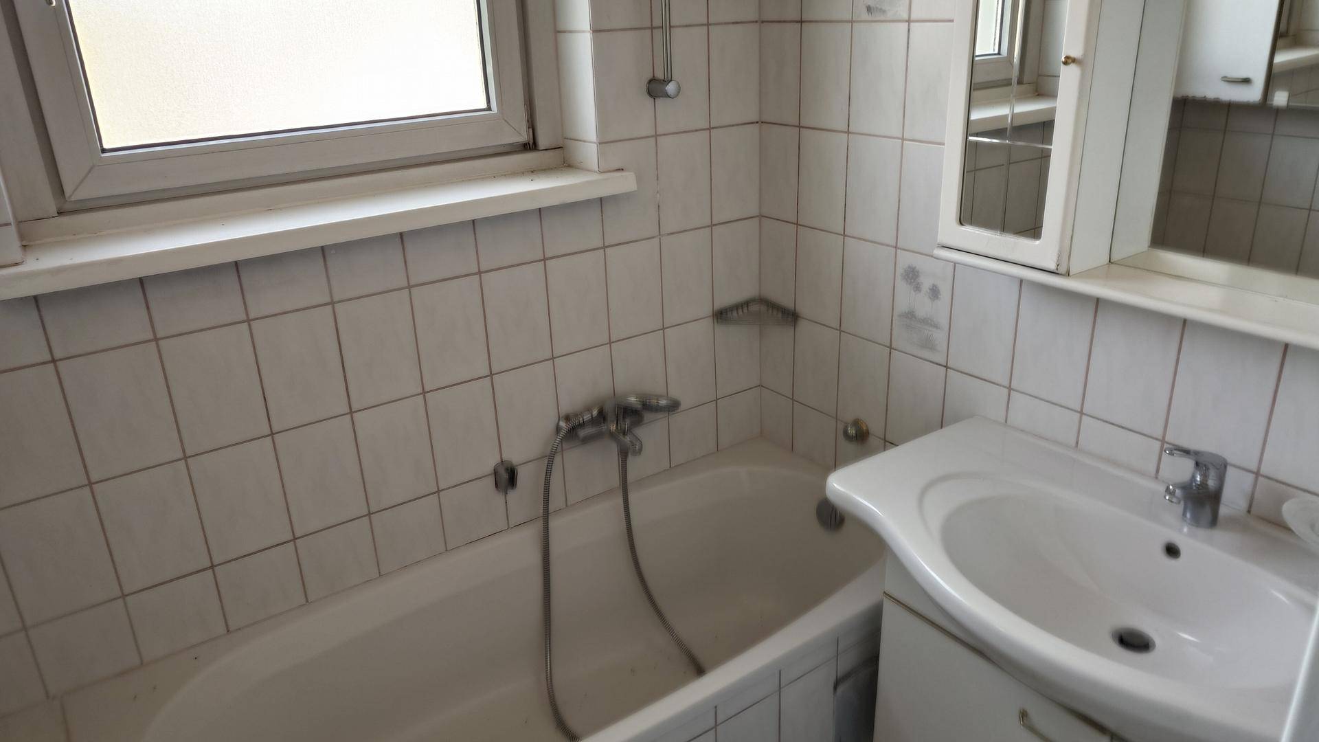 Funktionales Badezimmer mit Badewanne, Waschbecken und Spiegelschrank.
