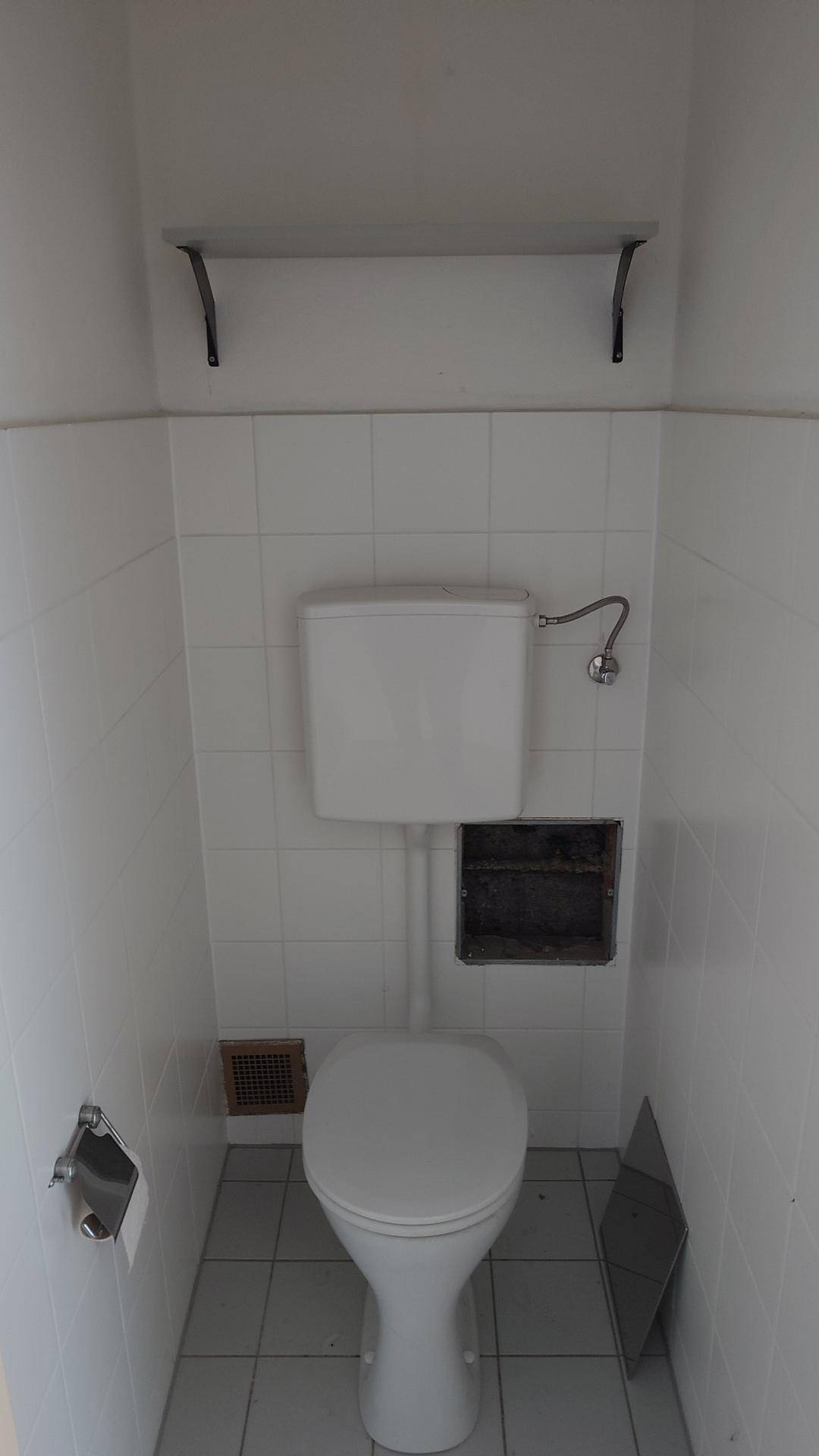Separates WC mit Fliesenboden und Wandfliesen in neutralem Farbton.