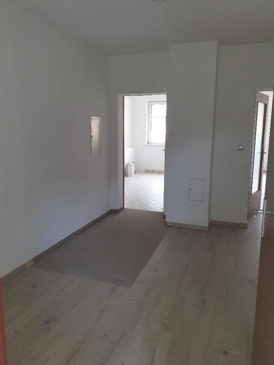 Heller Flur mit hellem Laminatboden, der zu weiteren leeren Räumen führt und gut gepflegt ist.