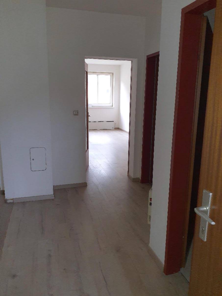Langer, heller Flur mit Laminatboden und Türen zu verschiedenen Zimmern, in gutem Zustand.