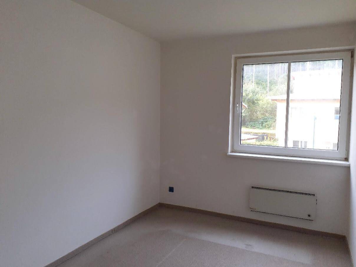 Leeres Zimmer mit hellem Fliesenboden und einem Fenster, das den Blick nach draußen freigibt.