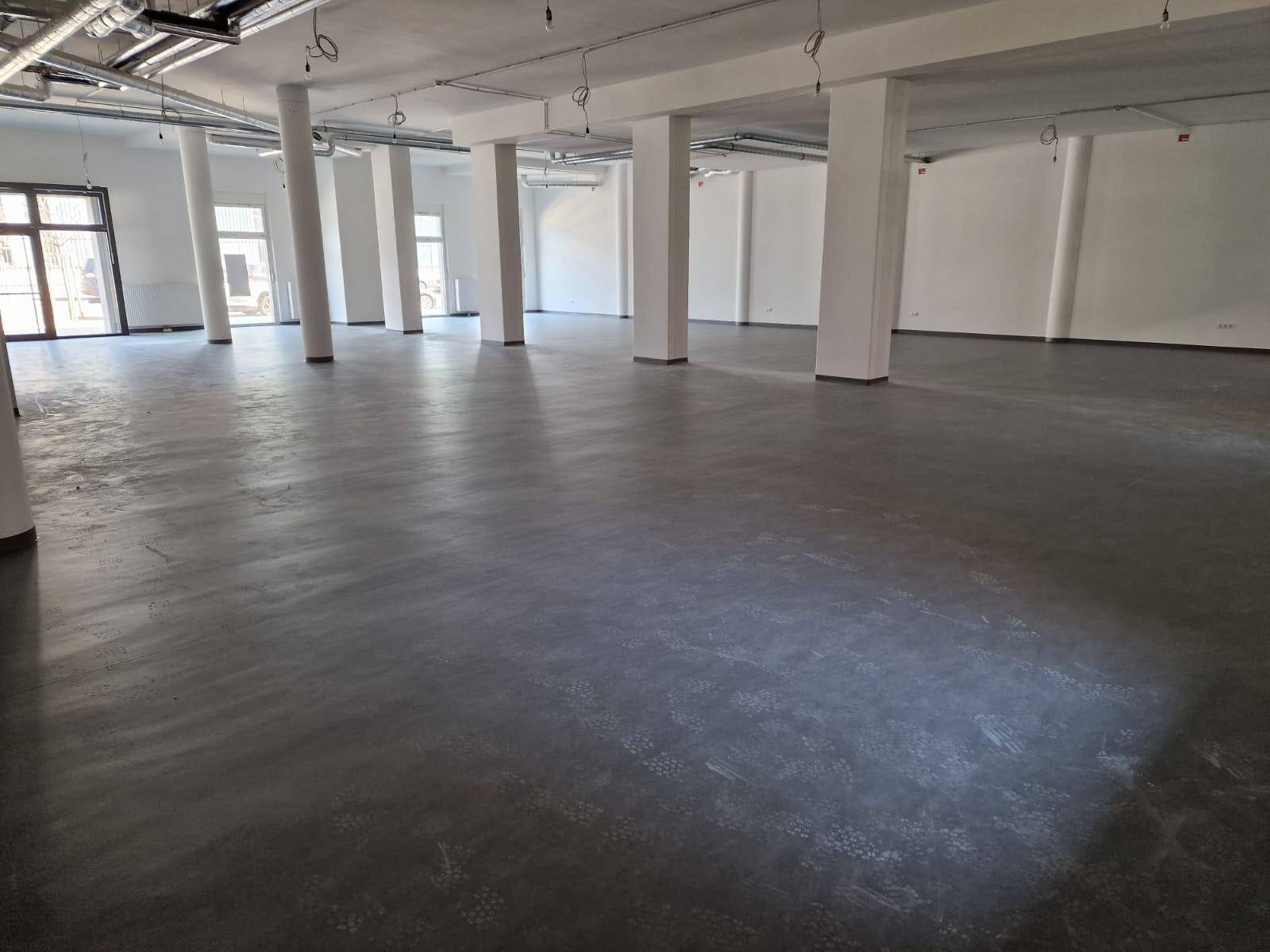Weitläufiger, leerer Gewerberaum mit vielen Säulen, Betonboden und sichtbaren Deckeninstallationen.