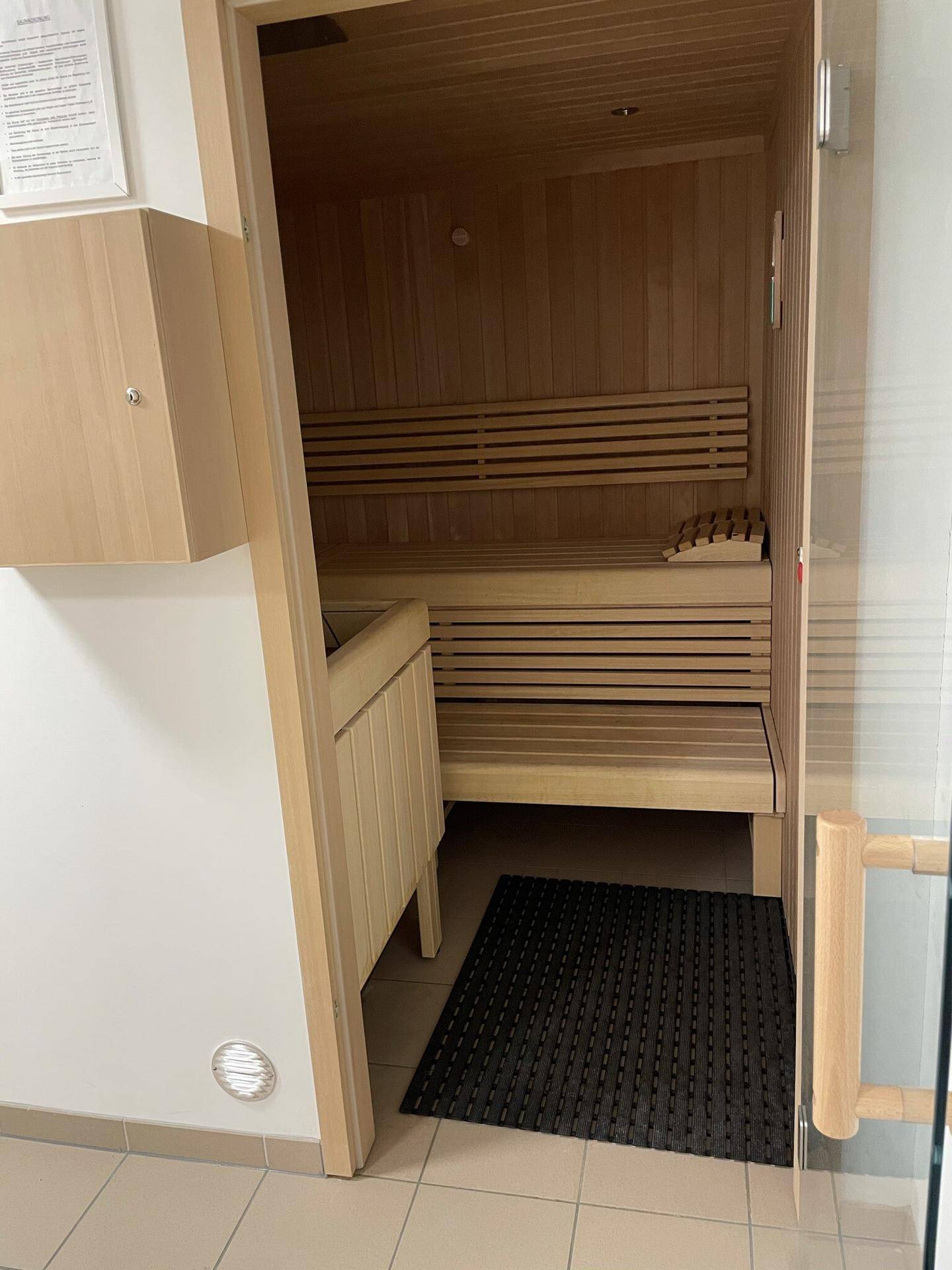 Holzvertäfelte Sauna mit Bänken und einem Saunaofen, bereit zur Nutzung.