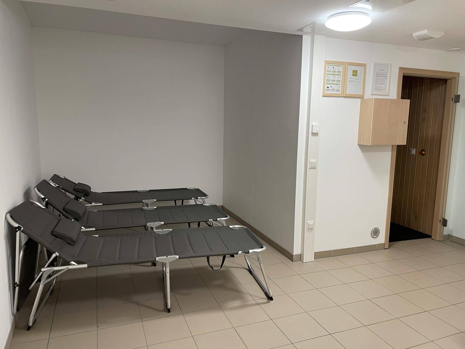 Entspannungsbereich mit mehreren Liegen und Zugang zu einer Sauna, Teil eines Wellnessbereichs.