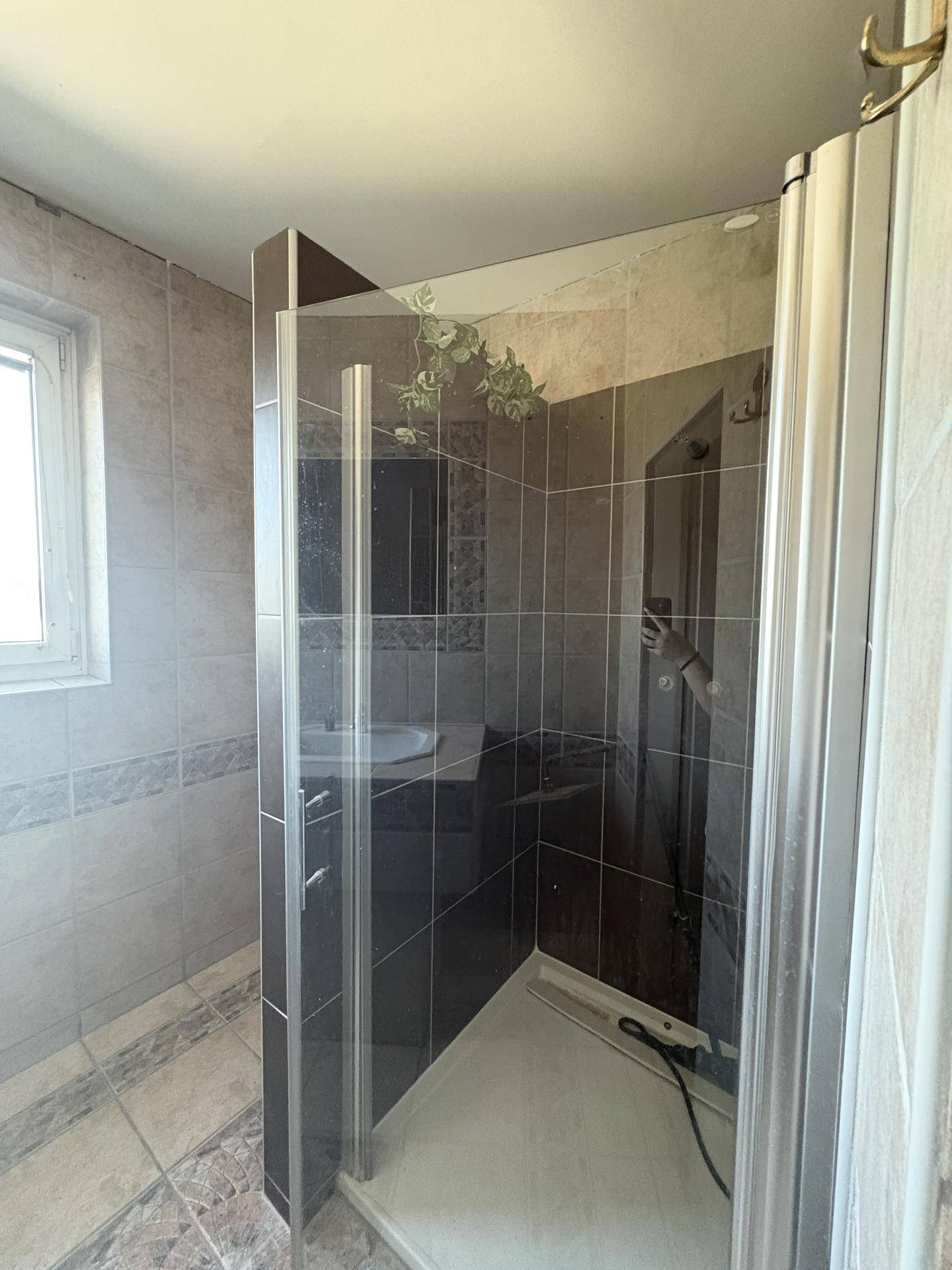 Badezimmer mit Fliesen und einer Duschkabine.