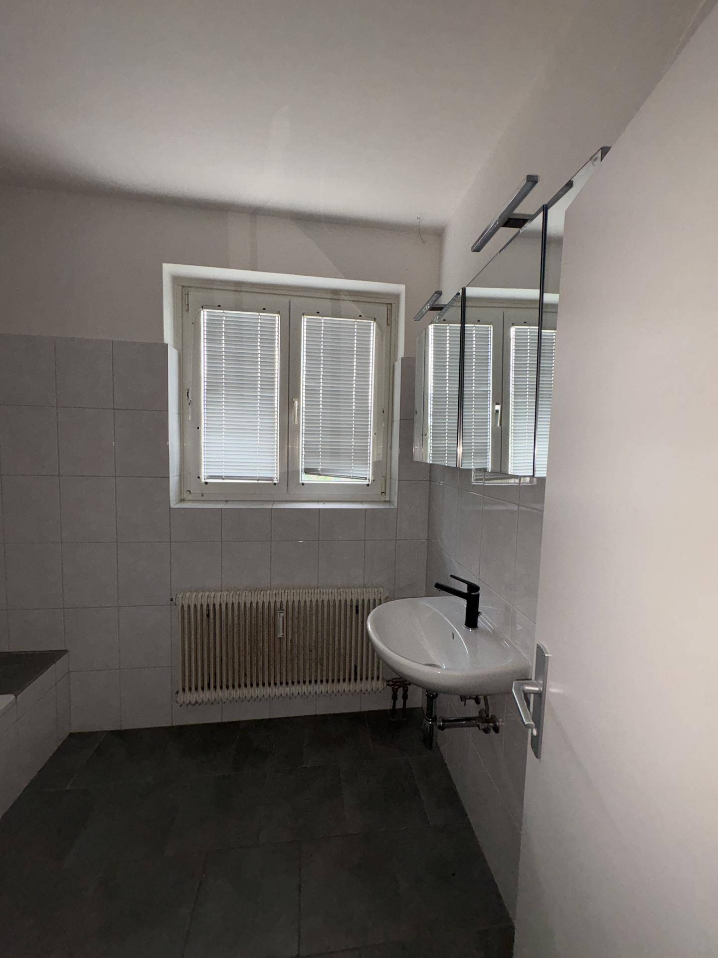 Badezimmer mit Waschbecken, Spiegelschrank und Fenster für natürliches Licht und Belüftung.