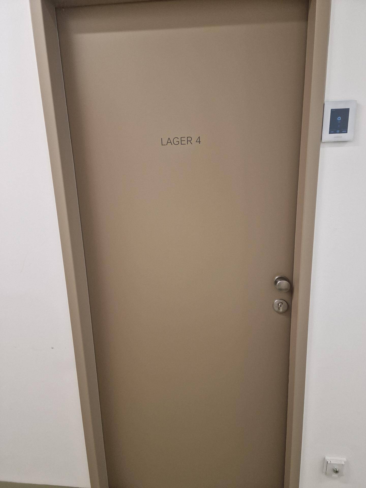 Eine geschlossene Tür mit der Aufschrift 'LAGER 4' in einem Flur oder Lagerbereich.