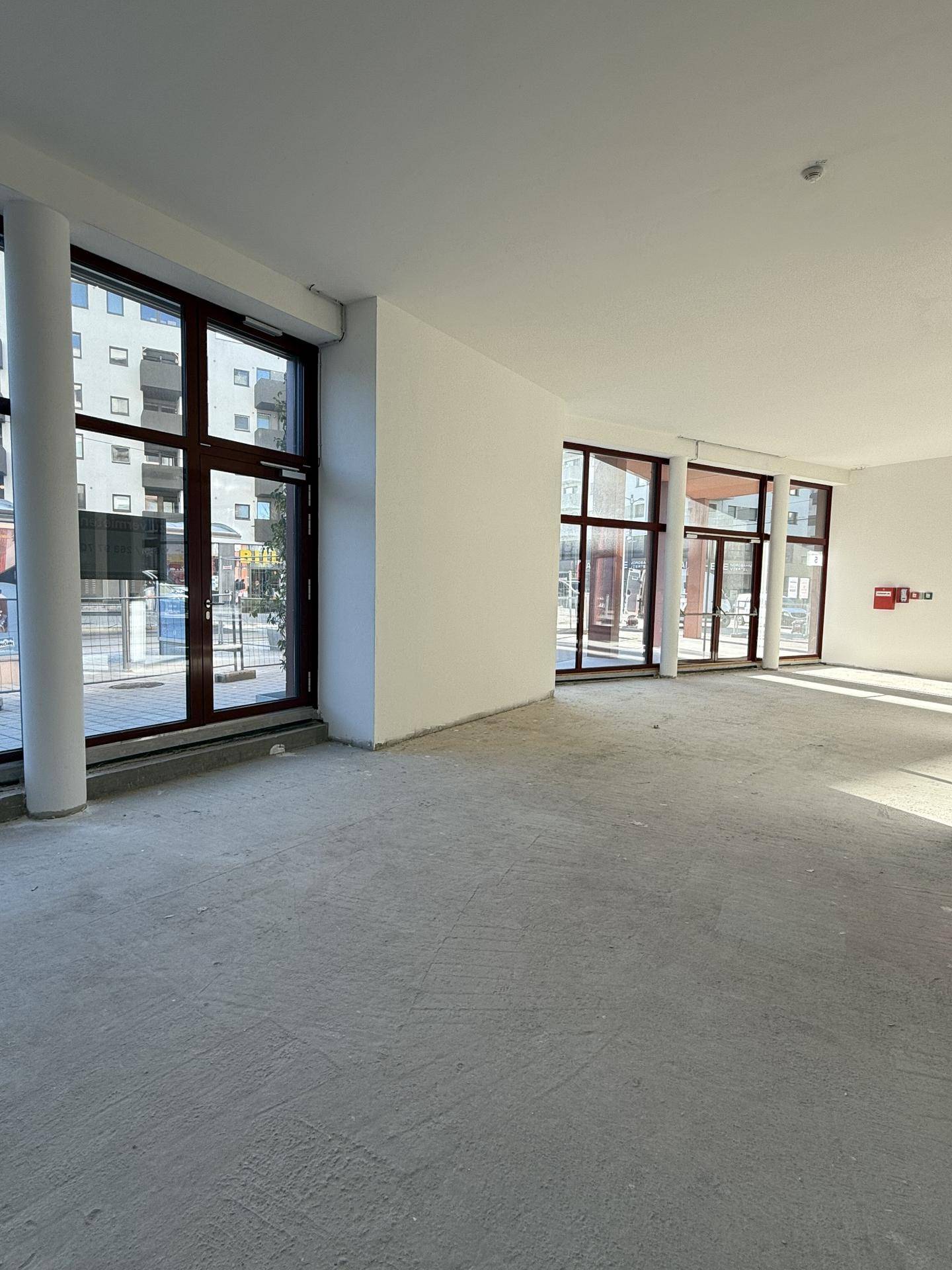 Geräumiger, leerer Gewerberaum mit großen Fenstern und Betonboden, bereit für den Ausbau.