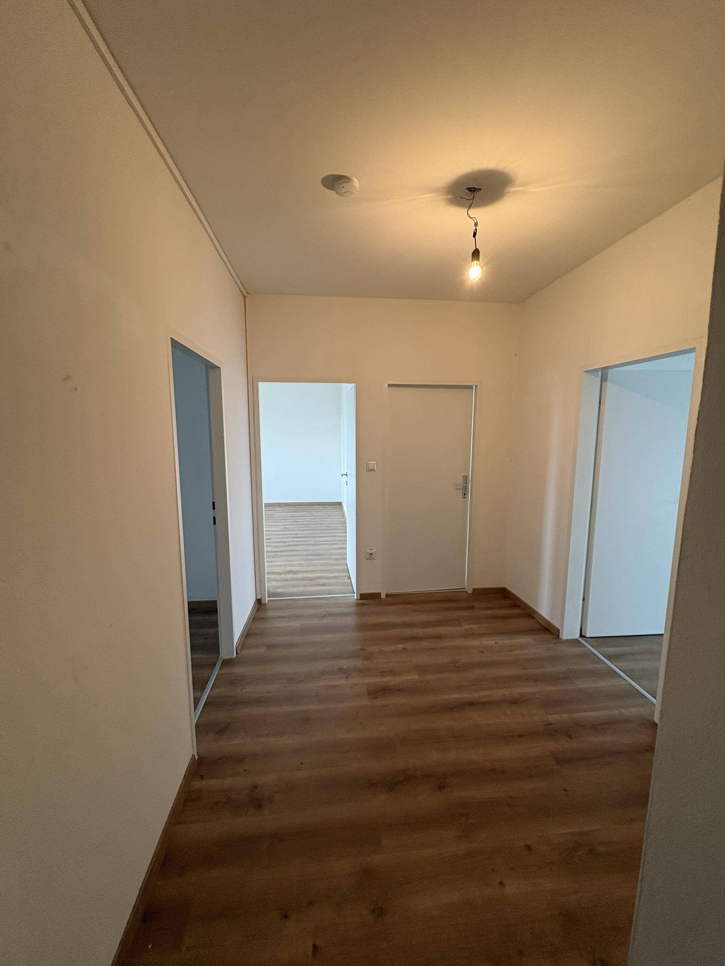 Heller Flur mit Laminatboden, der zu verschiedenen Zimmern der Wohnung führt.