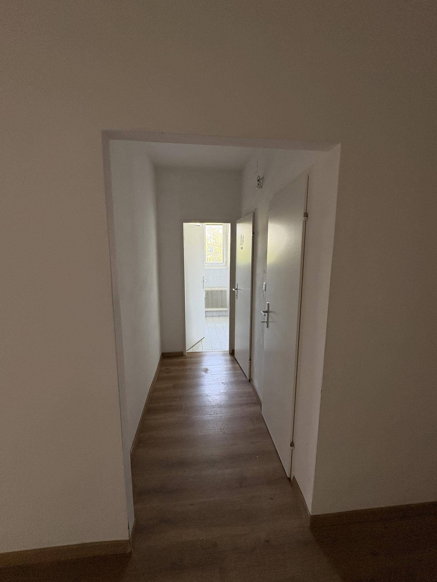 Langer, heller Flur mit Laminatboden und Türen zu angrenzenden Räumen.