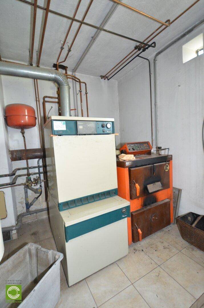 Heizungsraum mit älterem Heizkessel und sichtbaren Rohrleitungen, funktional und gut erhalten.