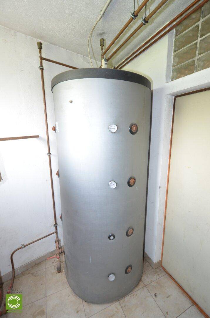Technikraum mit großem Warmwasserspeicher und sichtbaren Installationen, sauber und ordentlich.
