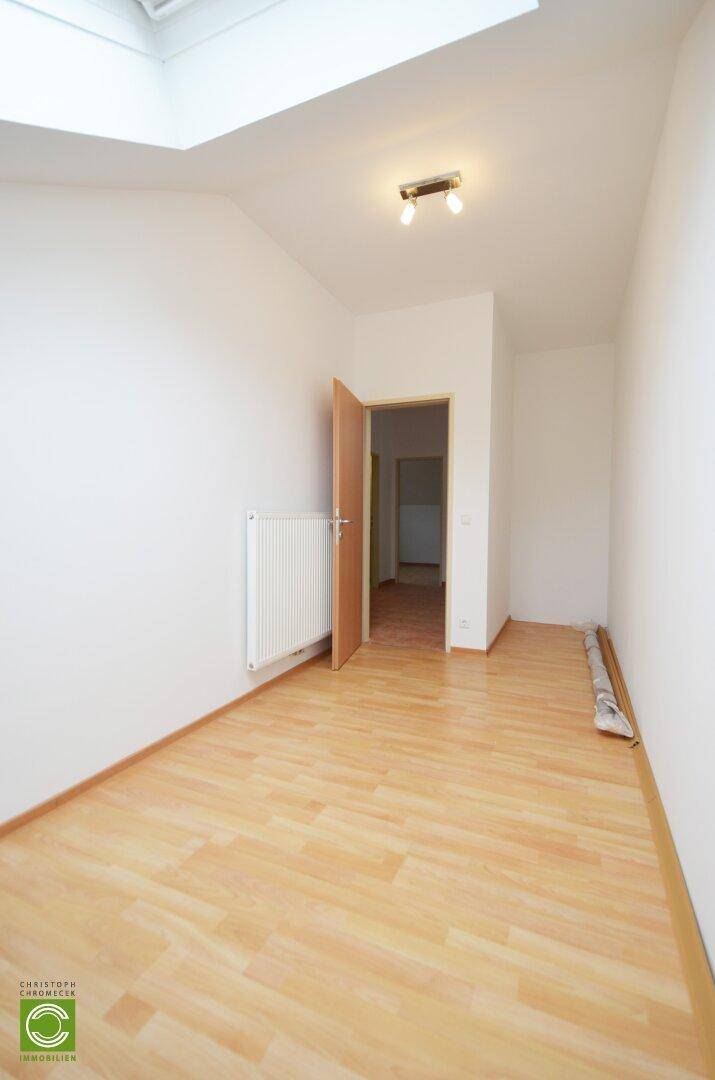 Geräumiges Zimmer im Dachgeschoss mit Laminatboden und Dachfenster.