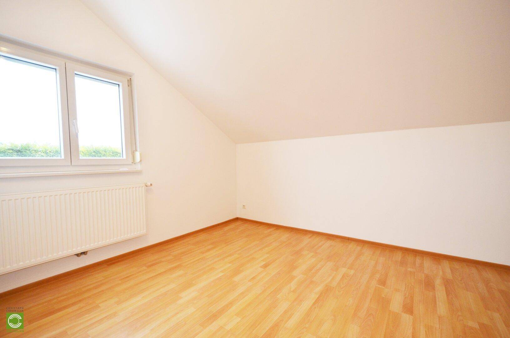 Helles Zimmer im Dachgeschoss mit Laminatboden und Schrägdach.