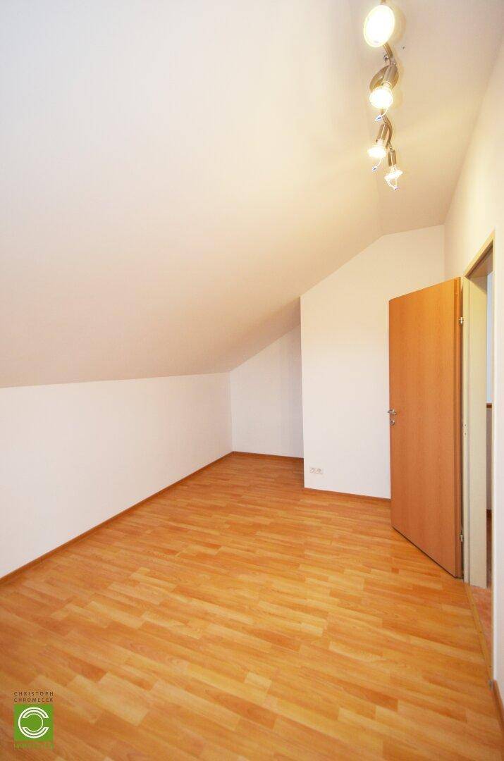 Geräumiges Zimmer im Dachgeschoss mit Laminatboden und Schrägdach.