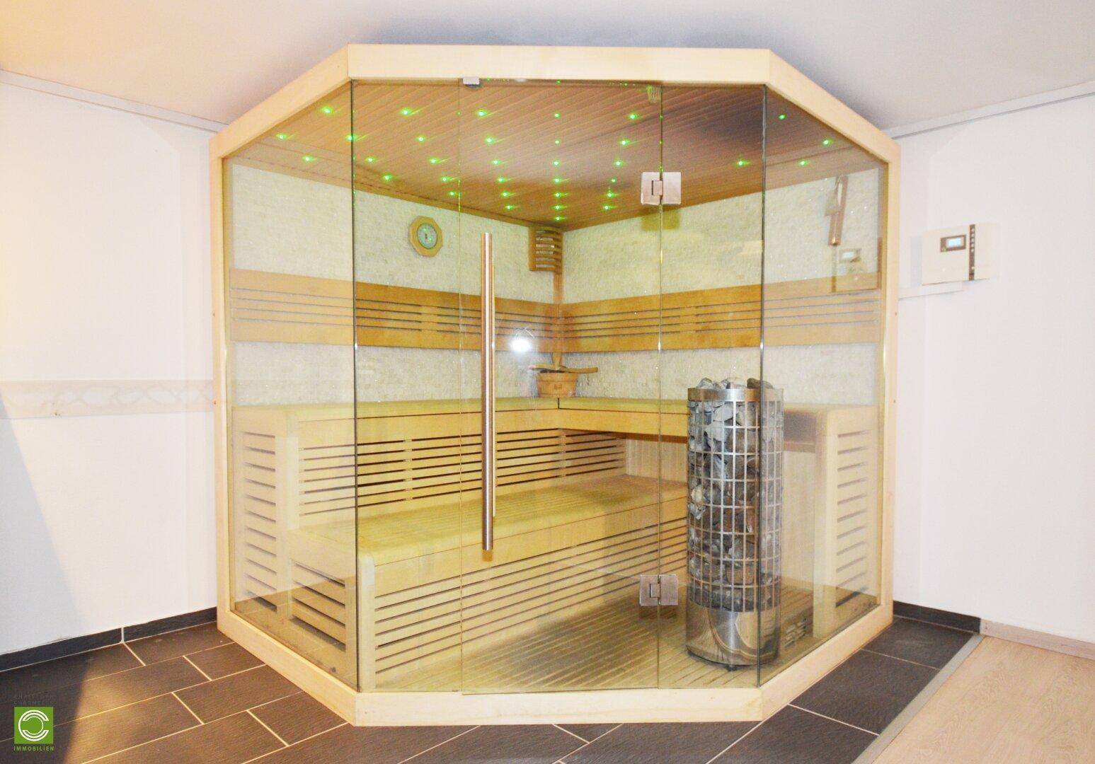 Moderne Sauna mit Glasfront, Holzverkleidung und Sternenhimmelbeleuchtung.