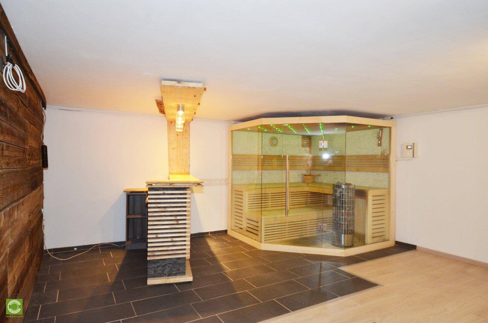 Geräumiger Wellnessbereich mit Sauna, Holzelementen und Fliesenboden.