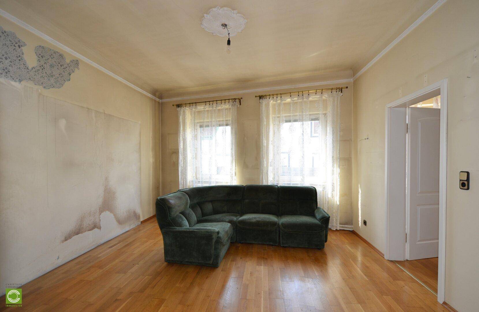 Geräumiges Wohnzimmer mit Parkettboden und einer großen Eckcouch, hell und einladend.