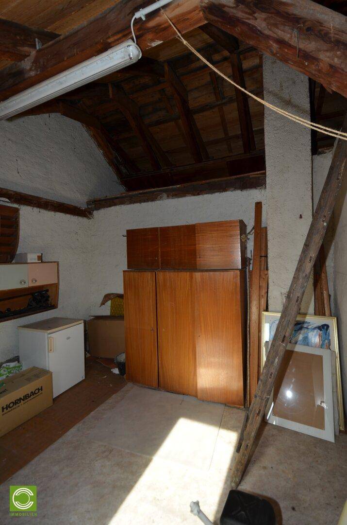 Abstellraum im Dachgeschoss mit Holzschränken und unfertigen Wänden, ideal für Lagerung.