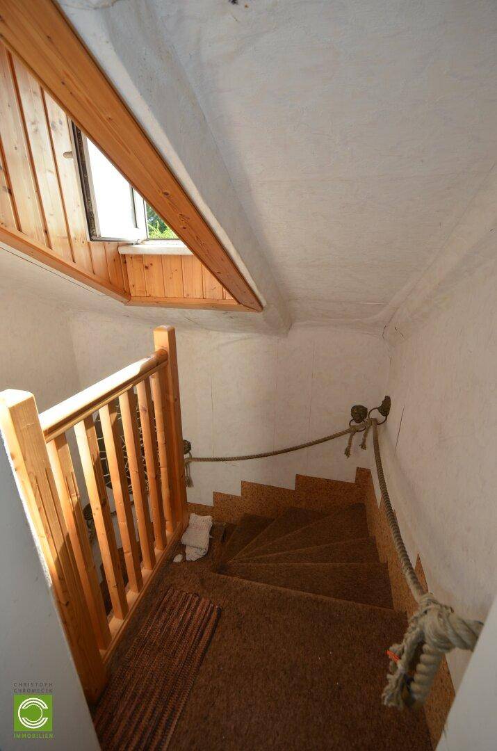 Treppenhaus mit Holzgeländer und Teppichboden, das zu den oberen Etagen führt.