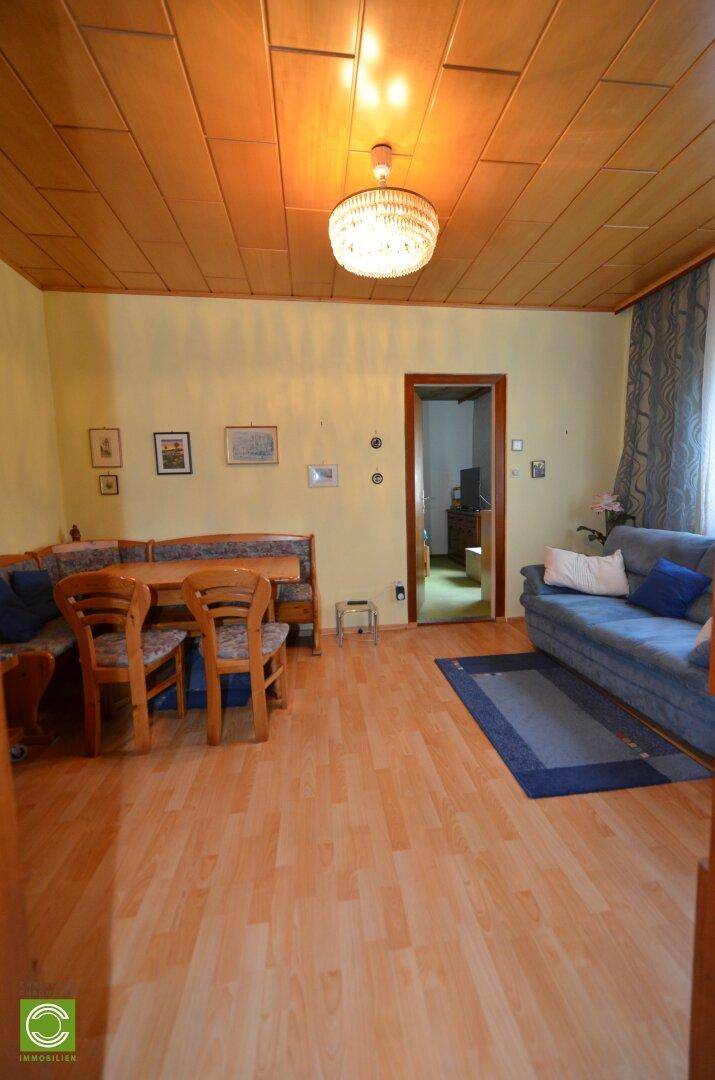 Wohn- und Essbereich mit Holzboden, Holzdecke und traditionellen Möbeln.