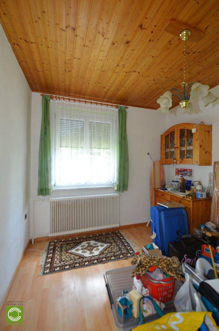 Schlafzimmer mit Holzboden, Holzdecke und Fenster mit Blick ins Grüne.