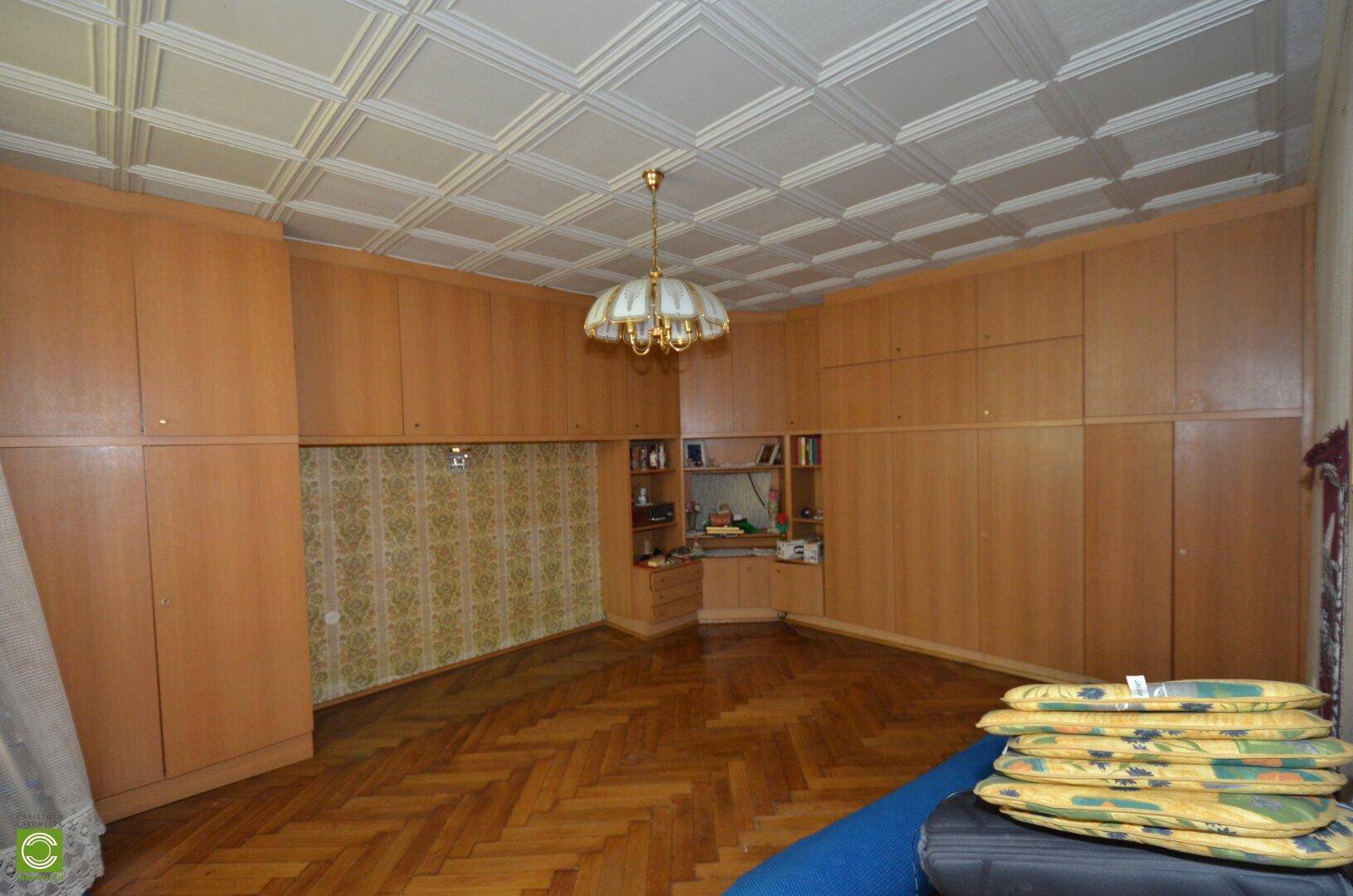 Geräumiges Schlafzimmer mit Parkettboden, Holzschränken und dekorativer Kassettendecke.