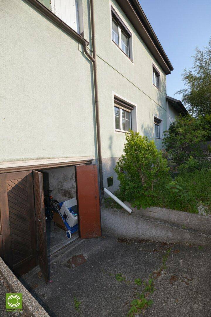 Seitenansicht des Hauses mit Garageneinfahrt und einem offenen Garagentor.
