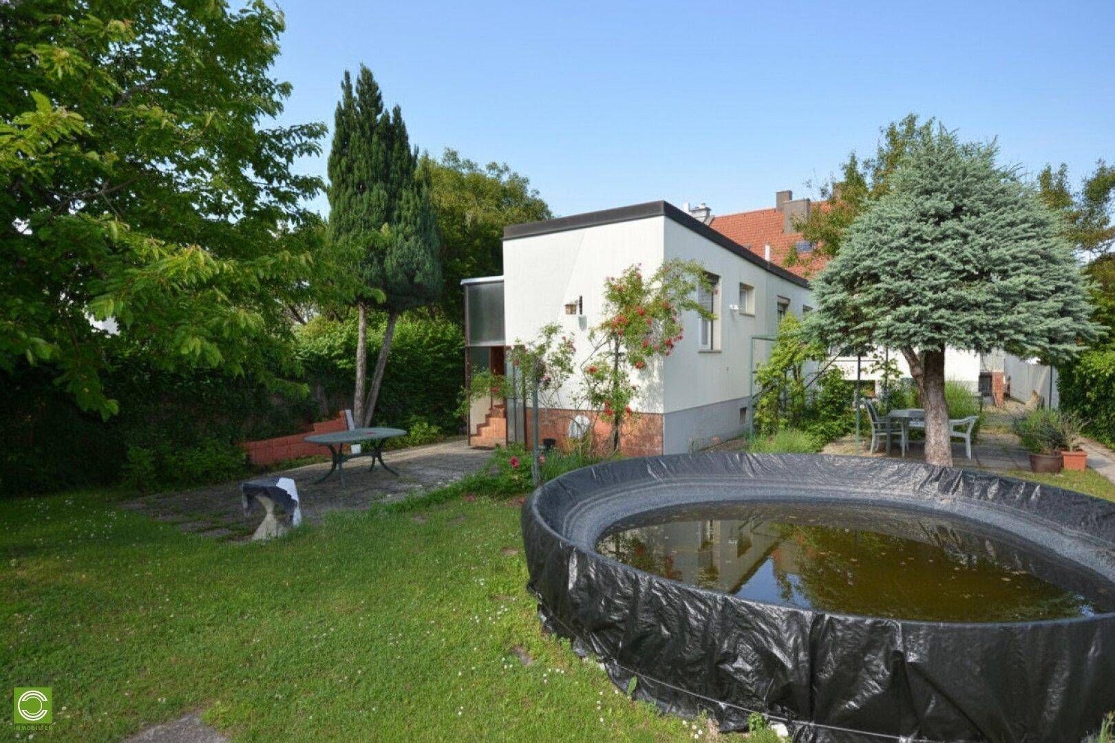 Großer Garten mit Rasenfläche, Bäumen und einem aufgestellten Pool im Freien.