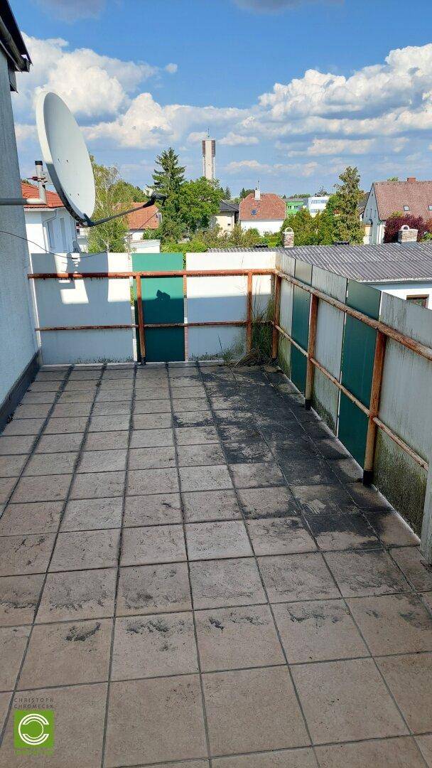 Großer gefliester Balkon mit Blick auf die Umgebung und einen Wasserturm in der Ferne.
