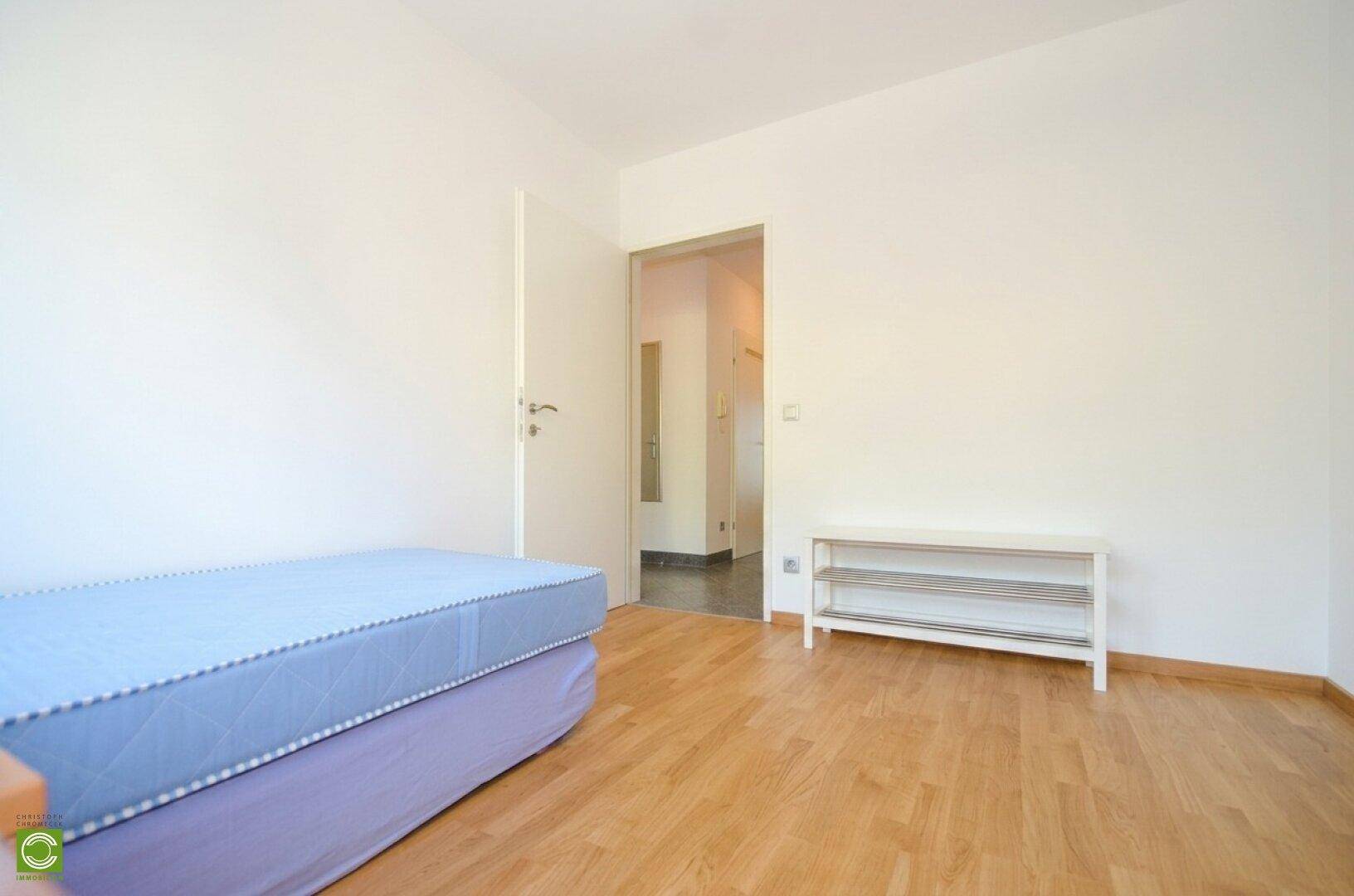 Schlafzimmer mit hellem Holzfußboden und Blick auf den Eingangsbereich des Zimmers.