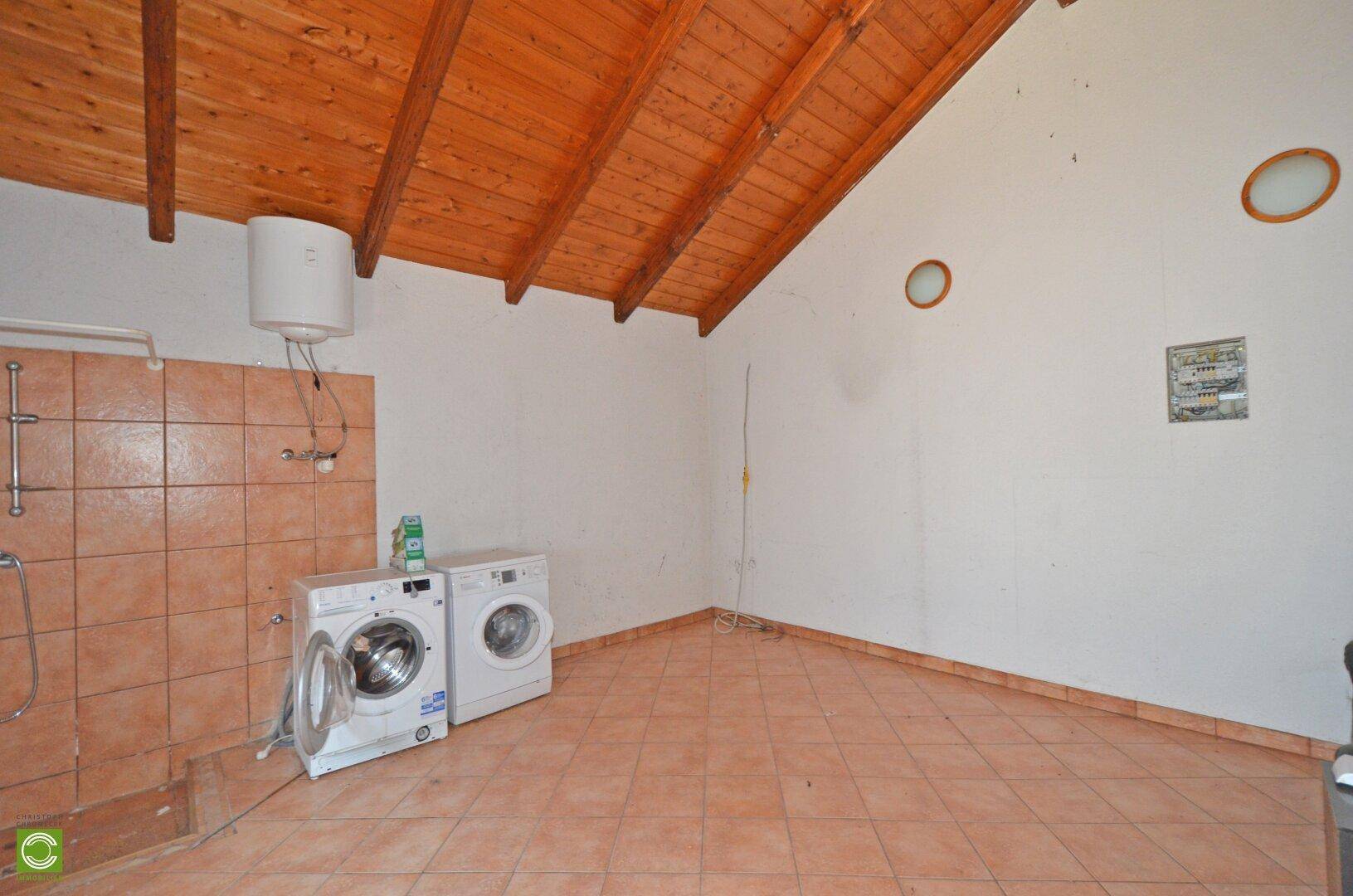 Hauswirtschaftsraum mit Waschmaschine, Trockner und Holzdachschräge, funktional eingerichtet.
