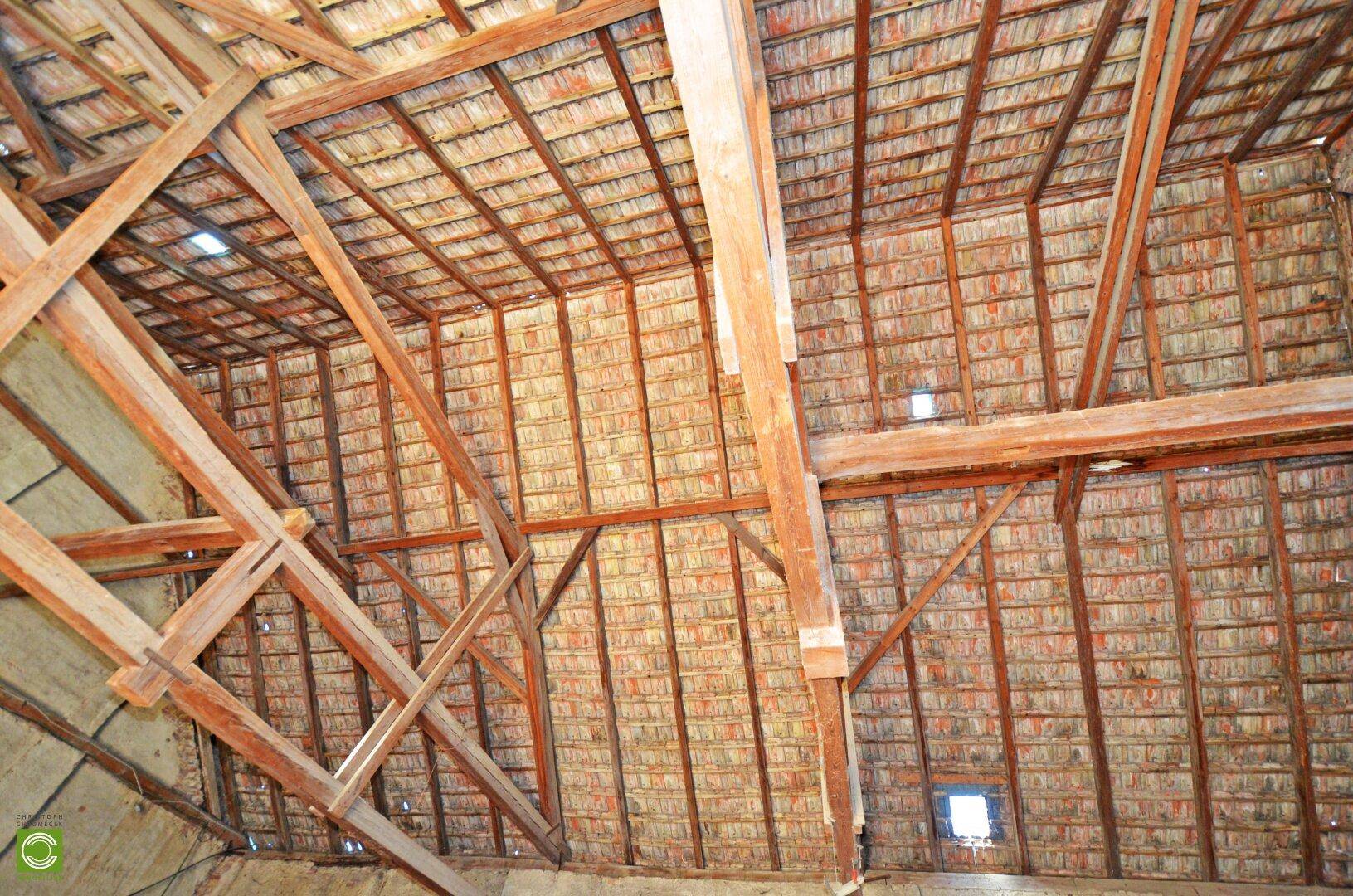 Dachkonstruktion mit sichtbaren Holzbalken und Ziegeln, die das rustikale Ambiente unterstreicht.