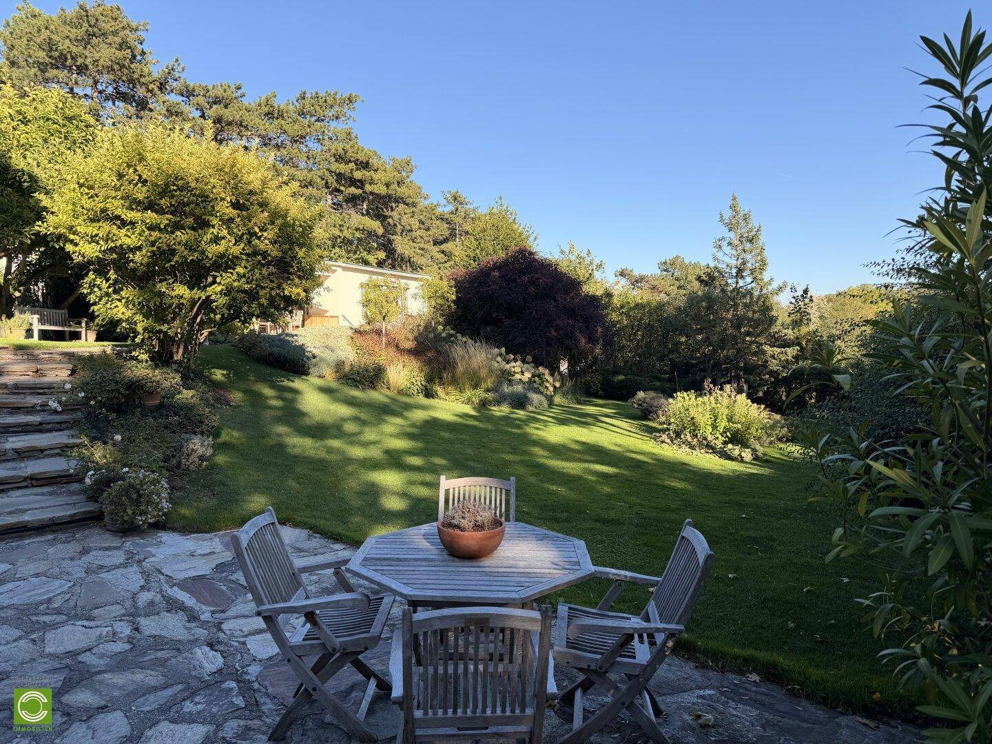 Gemütliche Steinterrasse mit Gartenmöbeln und weitem Blick auf den gepflegten Gartenbereich.